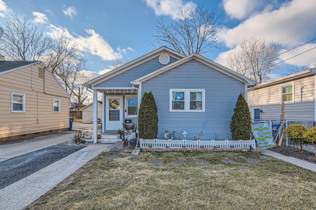bungalow-style home with a front lawn and fence