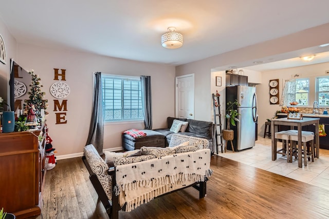 bedroom featuring freestanding refrigerator, baseboards, a sink, and light wood finished floors
