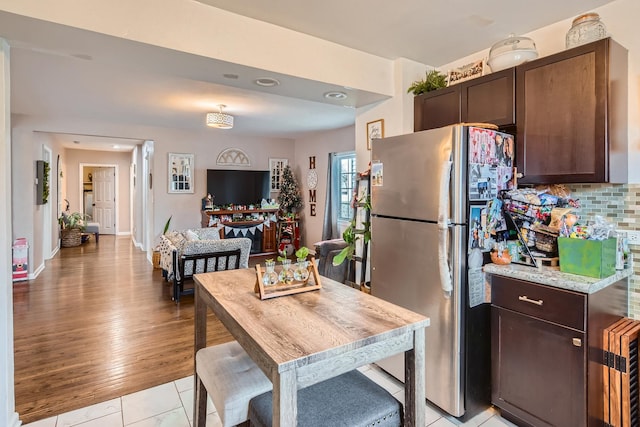 kitchen with freestanding refrigerator, backsplash, and dark brown cabinets