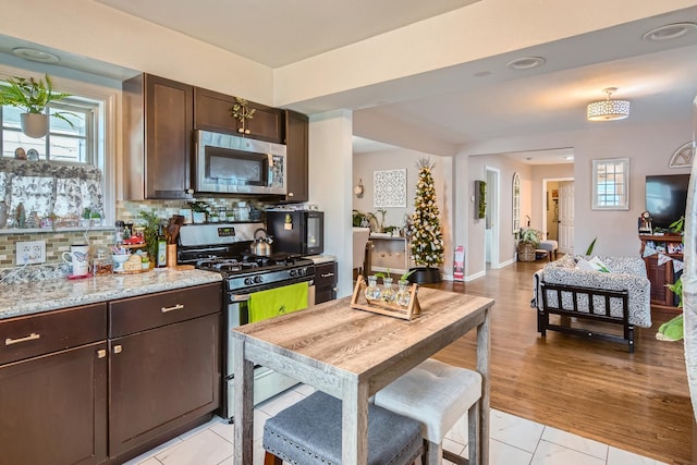 kitchen featuring appliances with stainless steel finishes, a wealth of natural light, backsplash, and dark brown cabinets