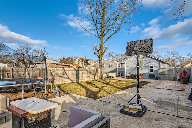 view of yard featuring a trampoline, a residential view, a gate, a fenced backyard, and a patio