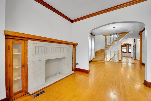 3016 N Major Ave, Chicago, IL 60634 - unfurnished living room with visible vents, crown molding, arched walkways, stairway, and a fireplace