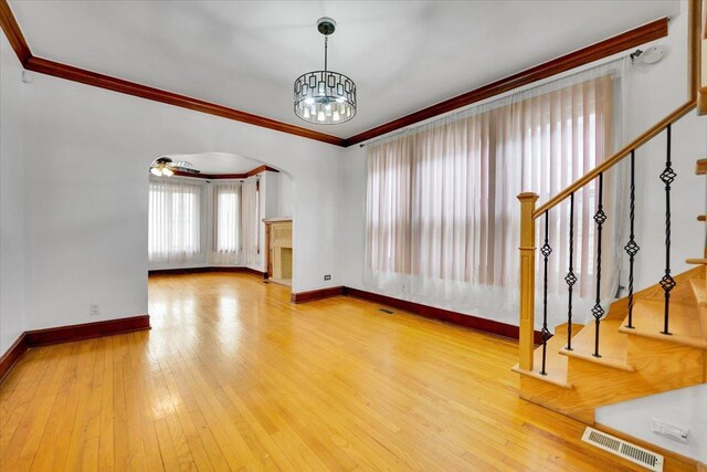 3016 N Major Ave, Chicago, IL 60634 - unfurnished living room with arched walkways, crown molding, an inviting chandelier, and visible vents