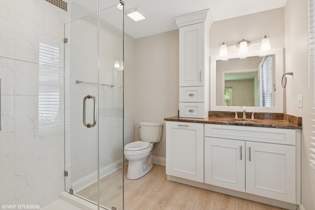 bathroom with toilet, a shower stall, wood finished floors, and vanity