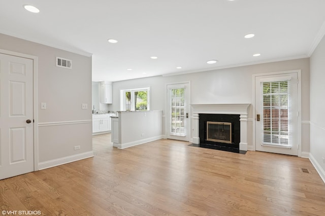 unfurnished living room featuring light wood finished floors, a high end fireplace, baseboards, ornamental molding, and recessed lighting