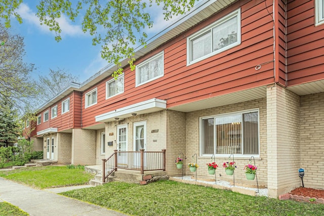 multi unit property featuring a front lawn and brick siding