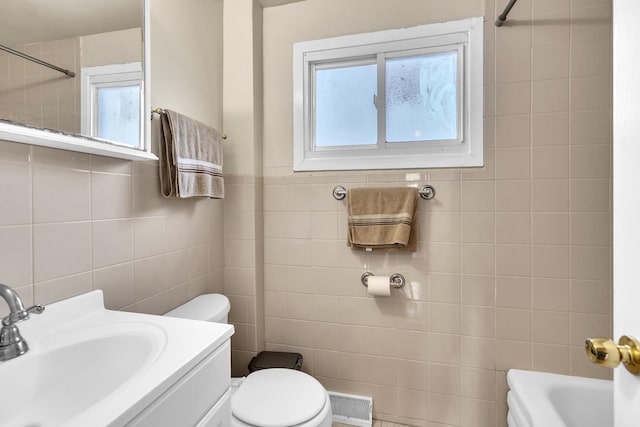 bathroom with tile walls, vanity, toilet, and visible vents