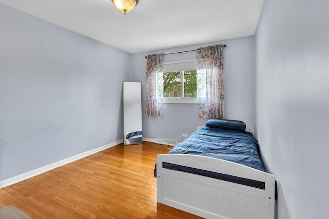 bedroom with baseboards, visible vents, and wood finished floors