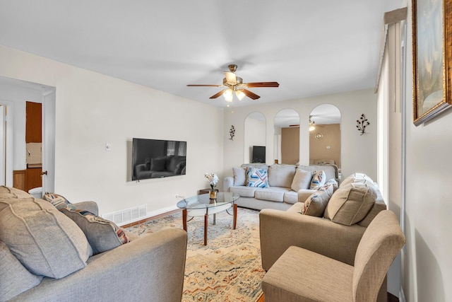 living room featuring visible vents, a ceiling fan, and arched walkways