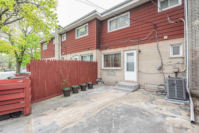back of house featuring fence, a patio, brick siding, central AC unit, and entry steps