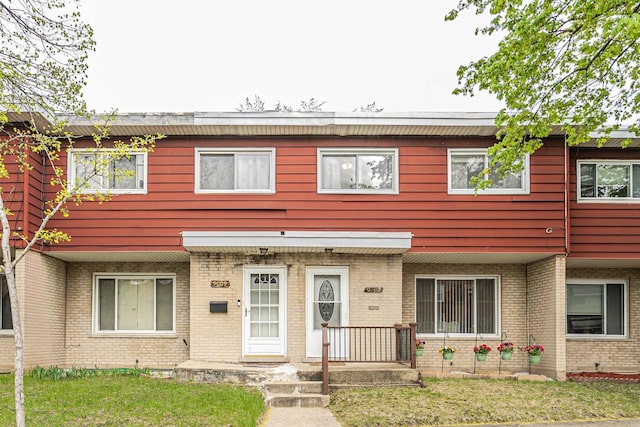 multi unit property featuring a front lawn and brick siding