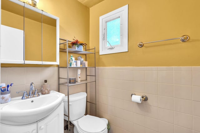 bathroom with vanity, toilet, and tile walls