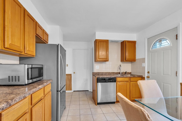 kitchen with decorative backsplash, brown cabinetry, stainless steel appliances, and light tile patterned flooring