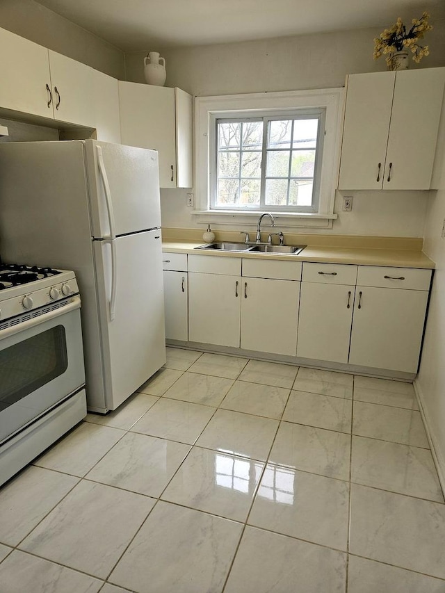 kitchen with white appliances, white cabinets, a sink, and light countertops