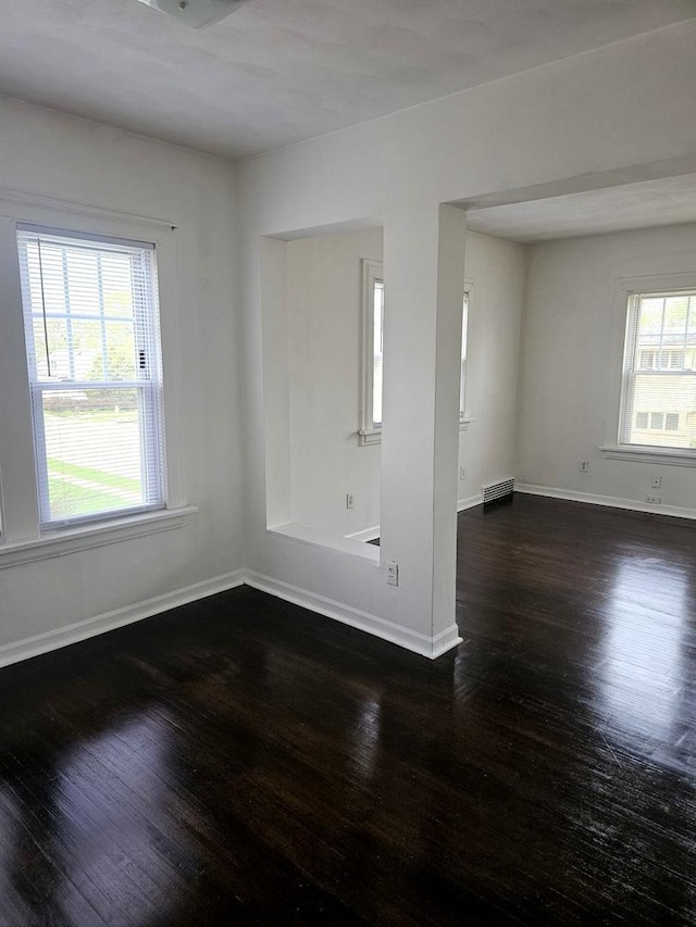 unfurnished room with baseboards, plenty of natural light, and wood finished floors