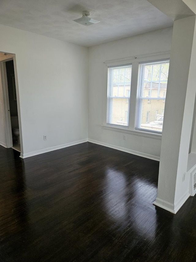 empty room with baseboards and dark wood finished floors