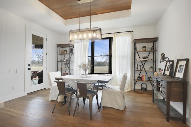 dining area with a raised ceiling, baseboards, wood ceiling, and wood finished floors