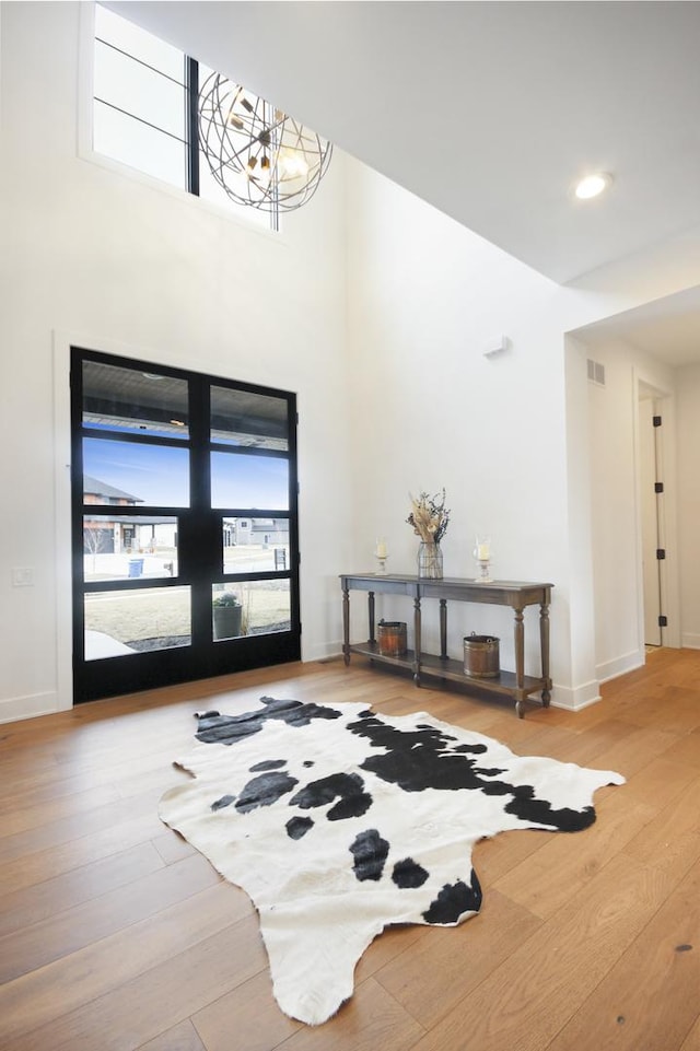 foyer entrance with baseboards, visible vents, a healthy amount of sunlight, and wood finished floors
