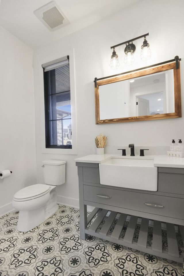bathroom with vanity, toilet, tile patterned floors, baseboards, and visible vents