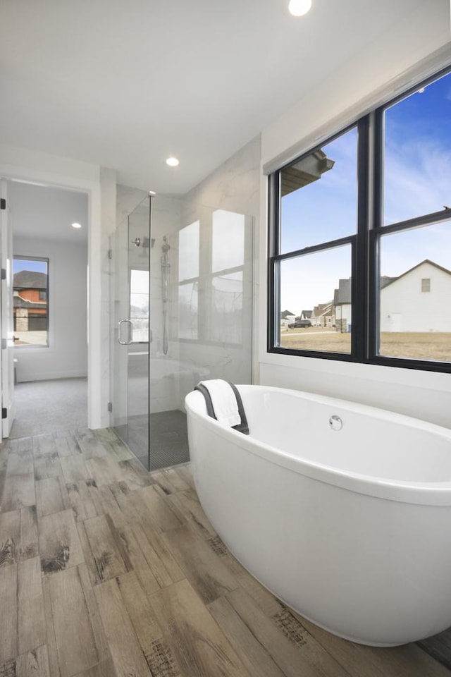 full bathroom featuring a freestanding bath, a stall shower, recessed lighting, and wood finished floors