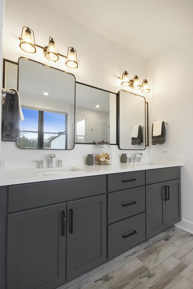 bathroom featuring double vanity, baseboards, a sink, and wood finished floors