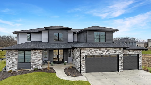 prairie-style house featuring driveway, a shingled roof, a front yard, and a garage