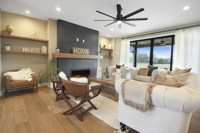 living area with recessed lighting, ceiling fan, wood finished floors, and a tile fireplace