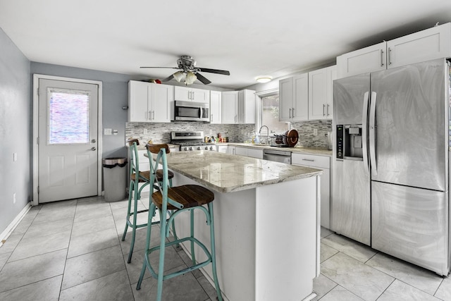 39540 N Channel View Dr, Antioch, IL 60002 - kitchen featuring appliances with stainless steel finishes, backsplash, white cabinets, light stone countertops, and a ceiling fan