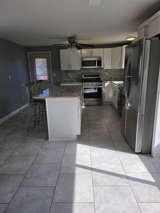 39540 N Channel View Dr, Antioch, IL 60002 - kitchen with stainless steel appliances, backsplash, light stone countertops, white cabinets, and light tile patterned floors