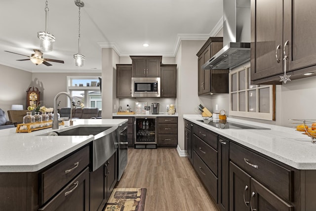 kitchen featuring ornamental molding, beverage cooler, wall chimney exhaust hood, stainless steel microwave, and a sink