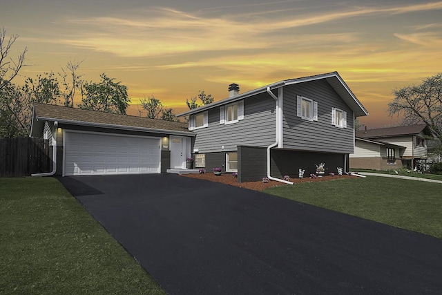 tri-level home with a lawn, fence, and a garage