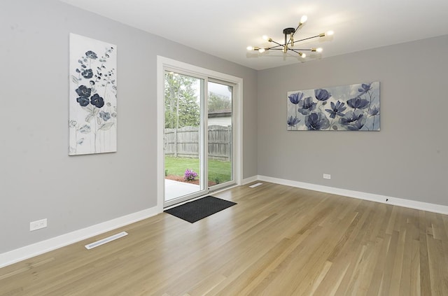 unfurnished dining area featuring baseboards, an inviting chandelier, light wood finished floors, and visible vents