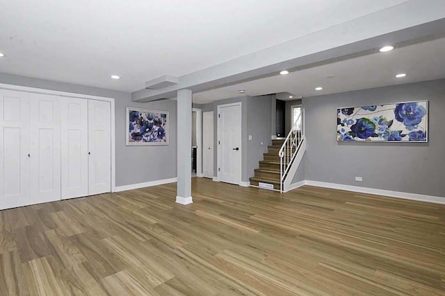 finished below grade area with stairway, baseboards, recessed lighting, and light wood finished floors