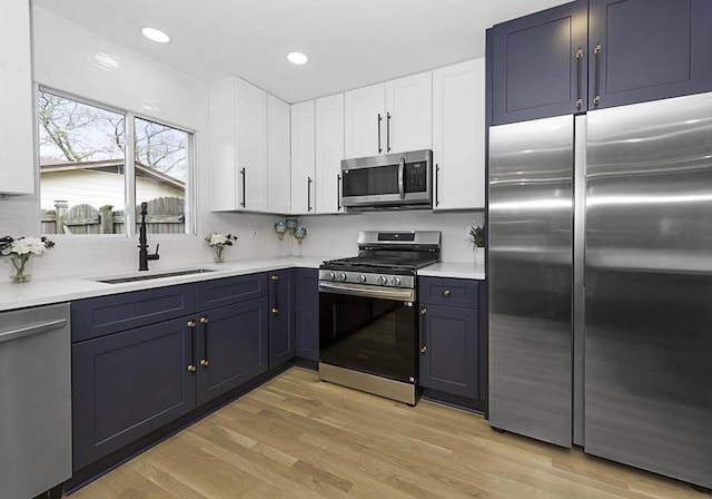 kitchen featuring a sink, appliances with stainless steel finishes, white cabinetry, and light countertops