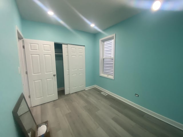 unfurnished bedroom with visible vents, a closet, wood finished floors, baseboards, and recessed lighting