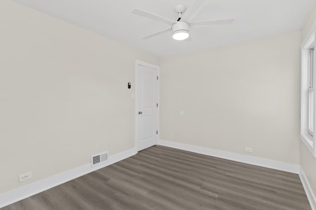 empty room with baseboards, visible vents, dark wood-style floors, and ceiling fan