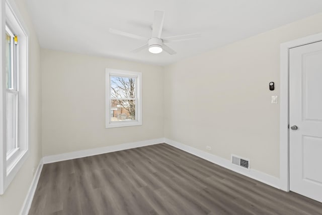 spare room featuring visible vents, dark wood finished floors, ceiling fan, and baseboards