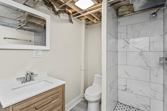 bathroom with vanity, a tile shower, toilet, and wood finished floors