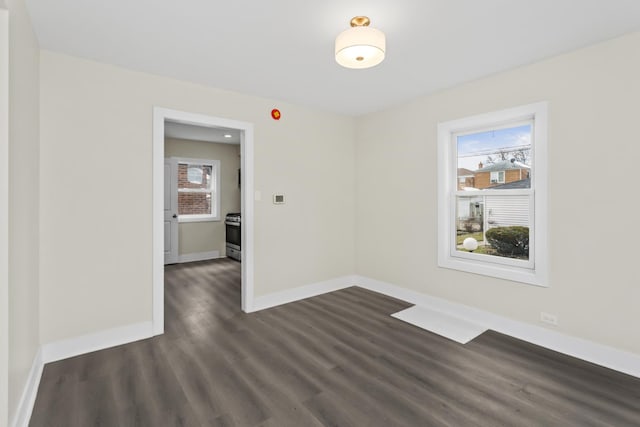 unfurnished room featuring baseboards and dark wood-type flooring
