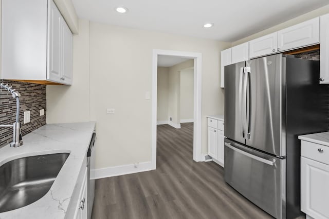 kitchen with dark wood-type flooring, freestanding refrigerator, decorative backsplash, and white cabinets