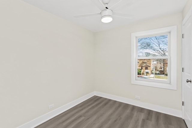 empty room featuring dark wood-type flooring, a ceiling fan, and baseboards