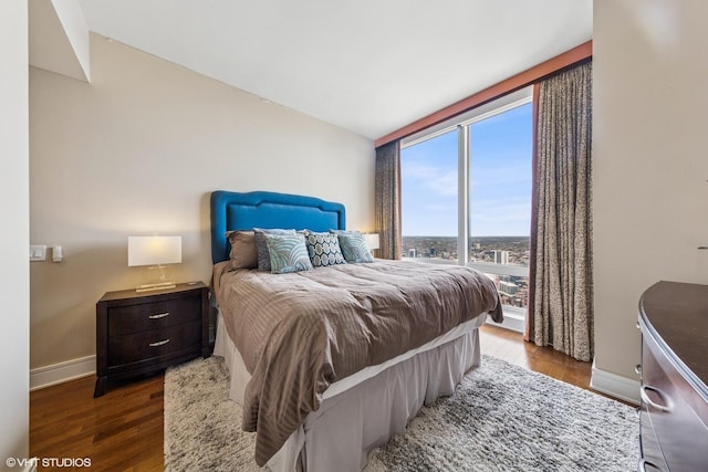bedroom with baseboards, lofted ceiling, wood finished floors, and expansive windows