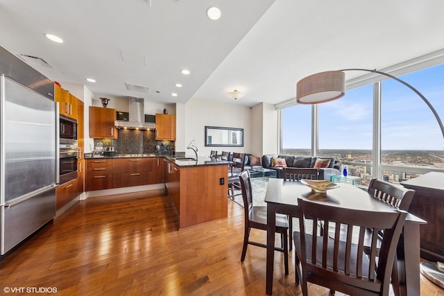 dining space with wood-type flooring, recessed lighting, visible vents, and a wall of windows
