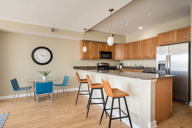 612 S Western Ave Unit 3, Chicago, IL 60612 - kitchen featuring visible vents, dark stone countertops, a kitchen bar, light wood finished floors, and appliances with stainless steel finishes