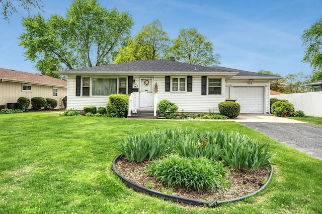 ranch-style home with driveway, an attached garage, fence, and a front yard
