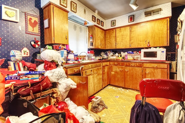 kitchen with wallpapered walls, brown cabinets, and white microwave