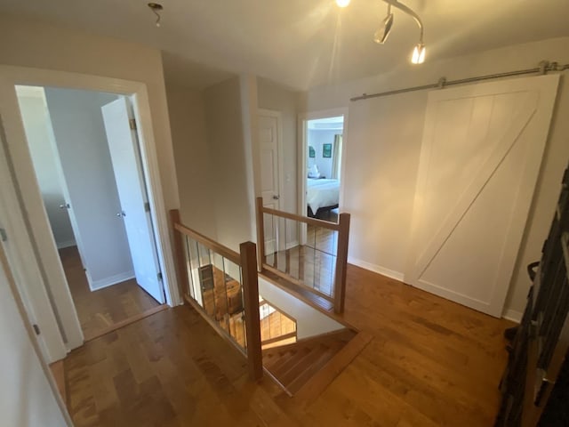 corridor with an upstairs landing, wood finished floors, and baseboards