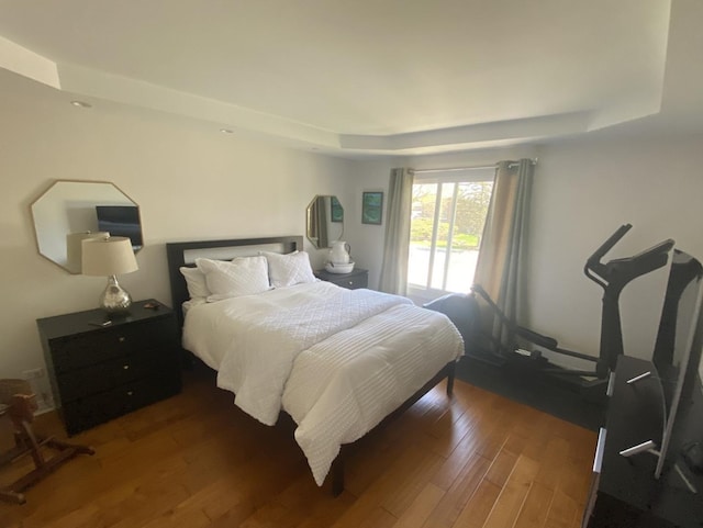 bedroom featuring a raised ceiling and wood finished floors