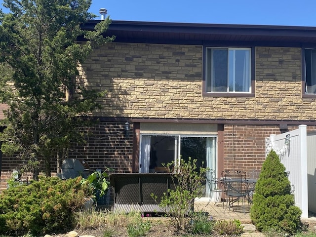 rear view of house featuring a patio, brick siding, and fence