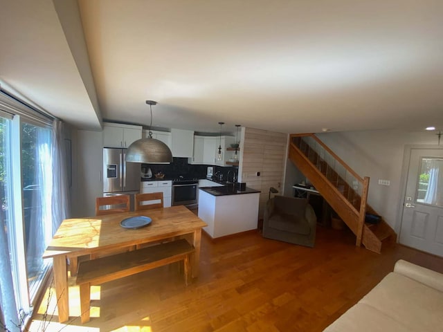 kitchen with appliances with stainless steel finishes, dark countertops, light wood-type flooring, white cabinets, and decorative backsplash